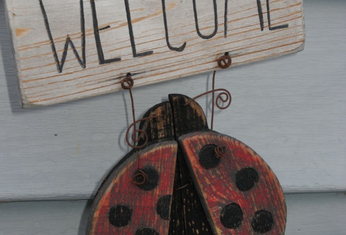 Wooden “all are welcome” Ladybug sign on wall