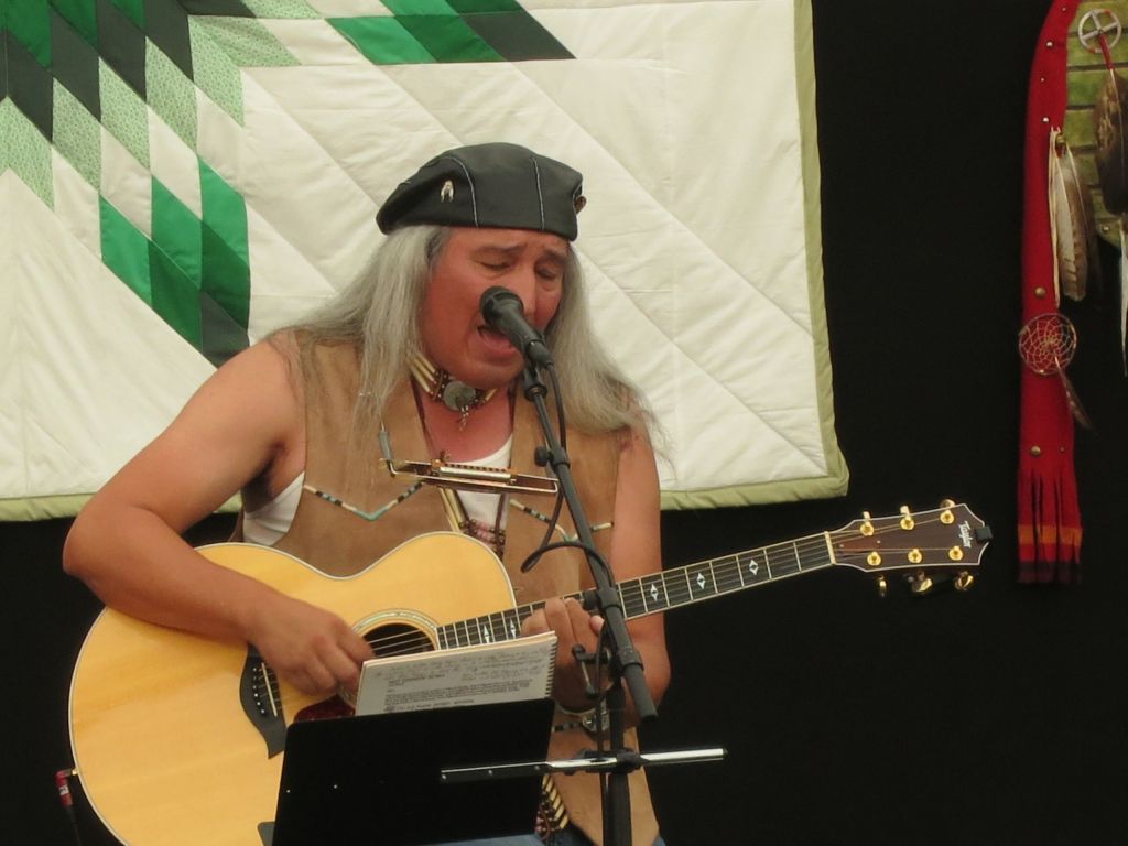 Jim Boyd playing guitar infront of a quilt hanging on the wall: By Paebi - Own work, CC BY-SA 3.0, https://commons.wikimedia.org/w/index.php?curid=26688298